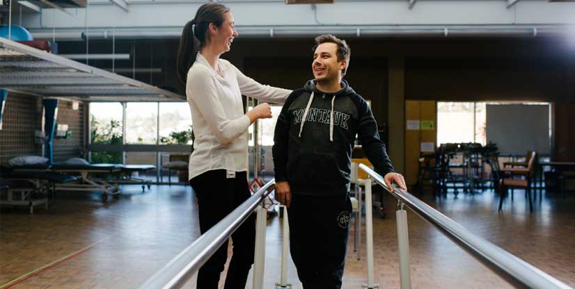 A physio works with a spinal rehabilitation patient