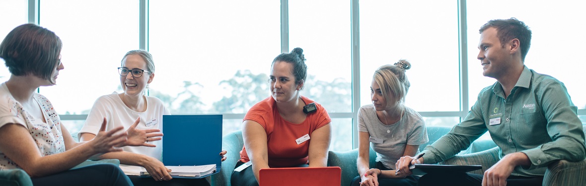 A group of allied health professionals with laptops and folders are having a discussion