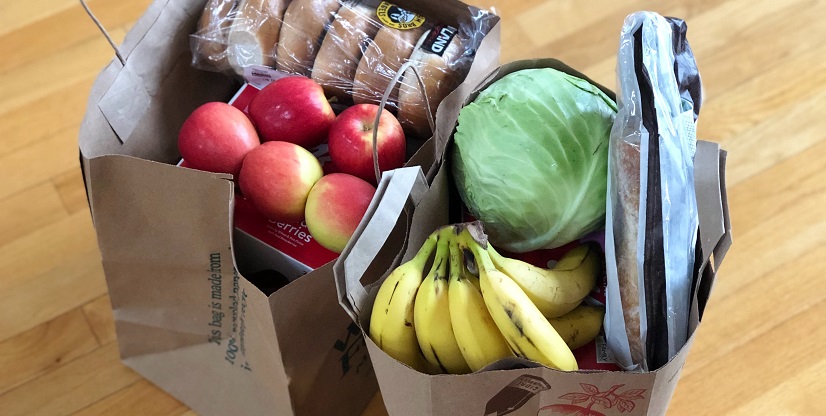 Groceries sitting on the floor in two paper bags