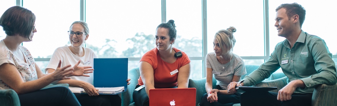 A group of allied health professionals with laptops and folders are having a discussion