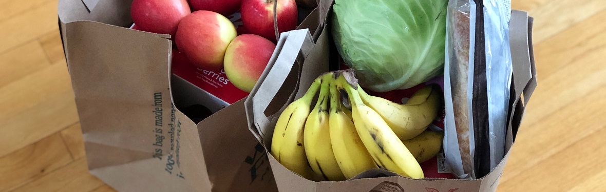 Groceries sitting on the floor in two paper bags